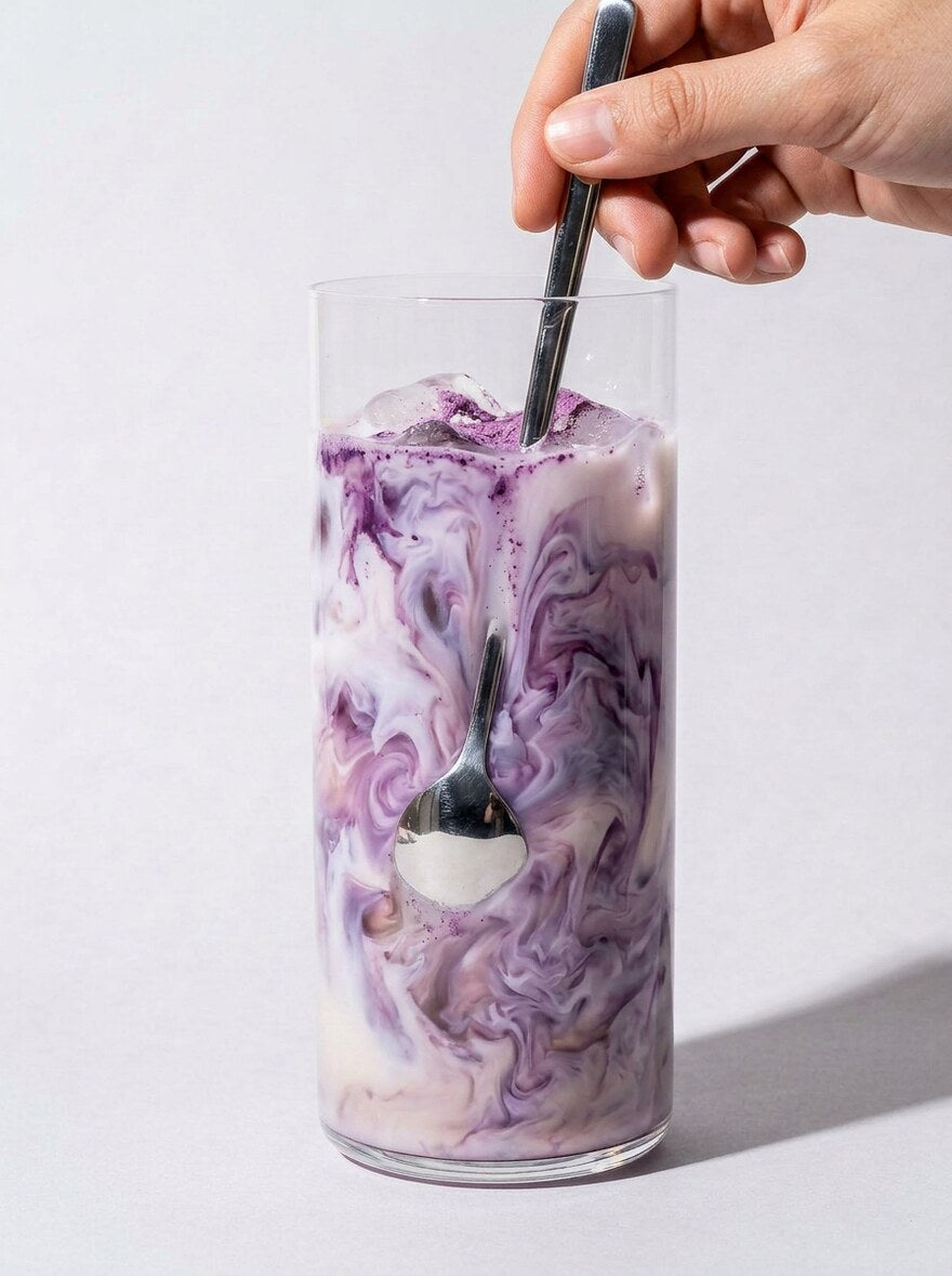 Latte ube violet servi dans une tasse en céramique blanche, lumière du matin